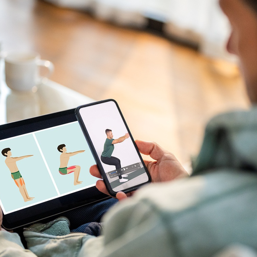 Ein Mann schaut auf Smartphone und Tablet eine Sportübung an